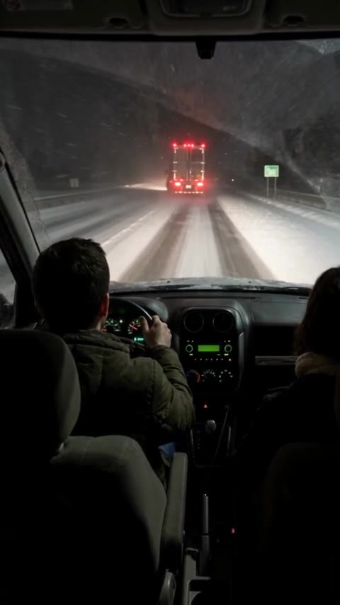 A jackknifed semi blocking a frozen Illinois bridge seen through a windshield in a blizzard - Ankin Law dramatization