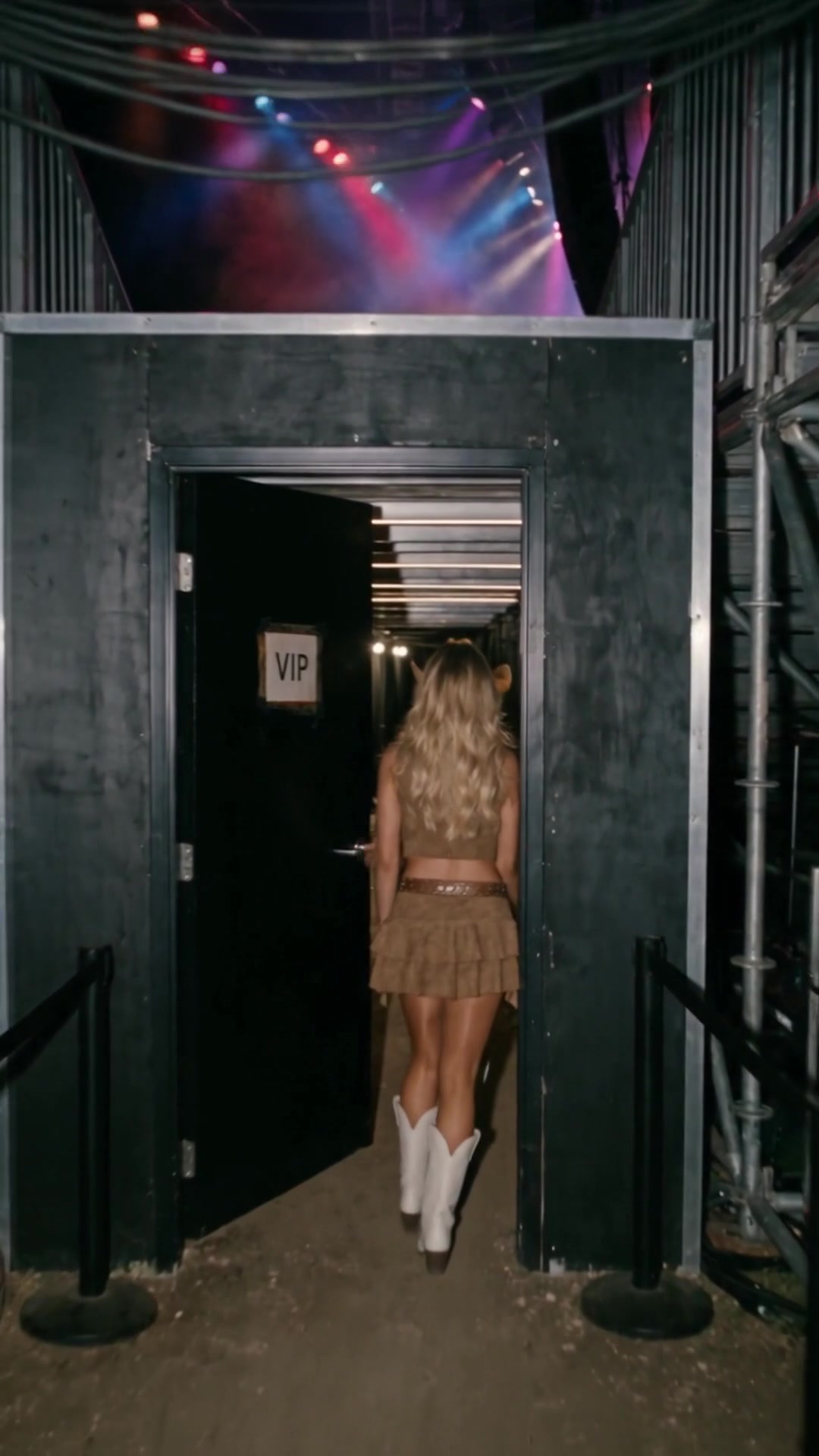 A young woman in a cowboy hat and white boots going through a door marked VIP under a concert stage - Ankin Law dramatization