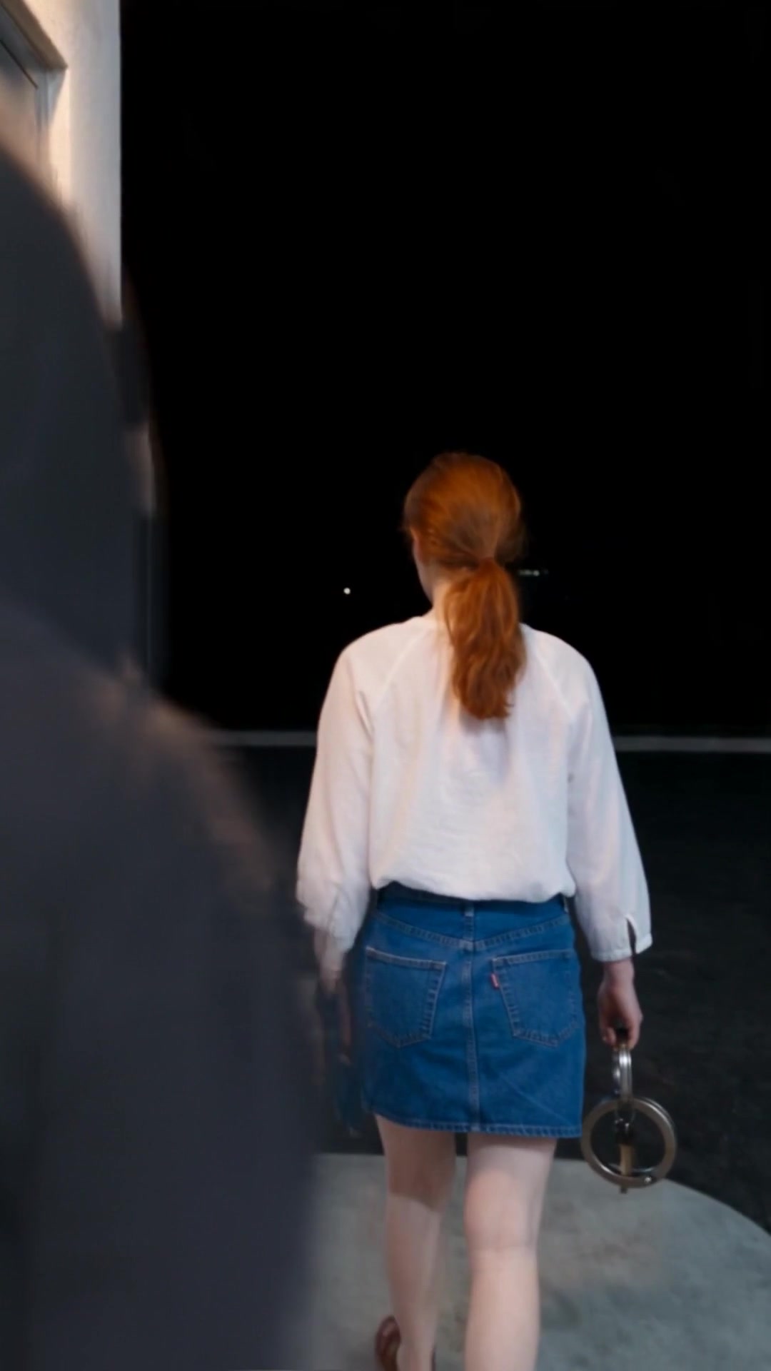 A young woman with red hair walking to the outside restroom of a gas station at night as a hooded man steps into view behind her - Ankin Law dramatization