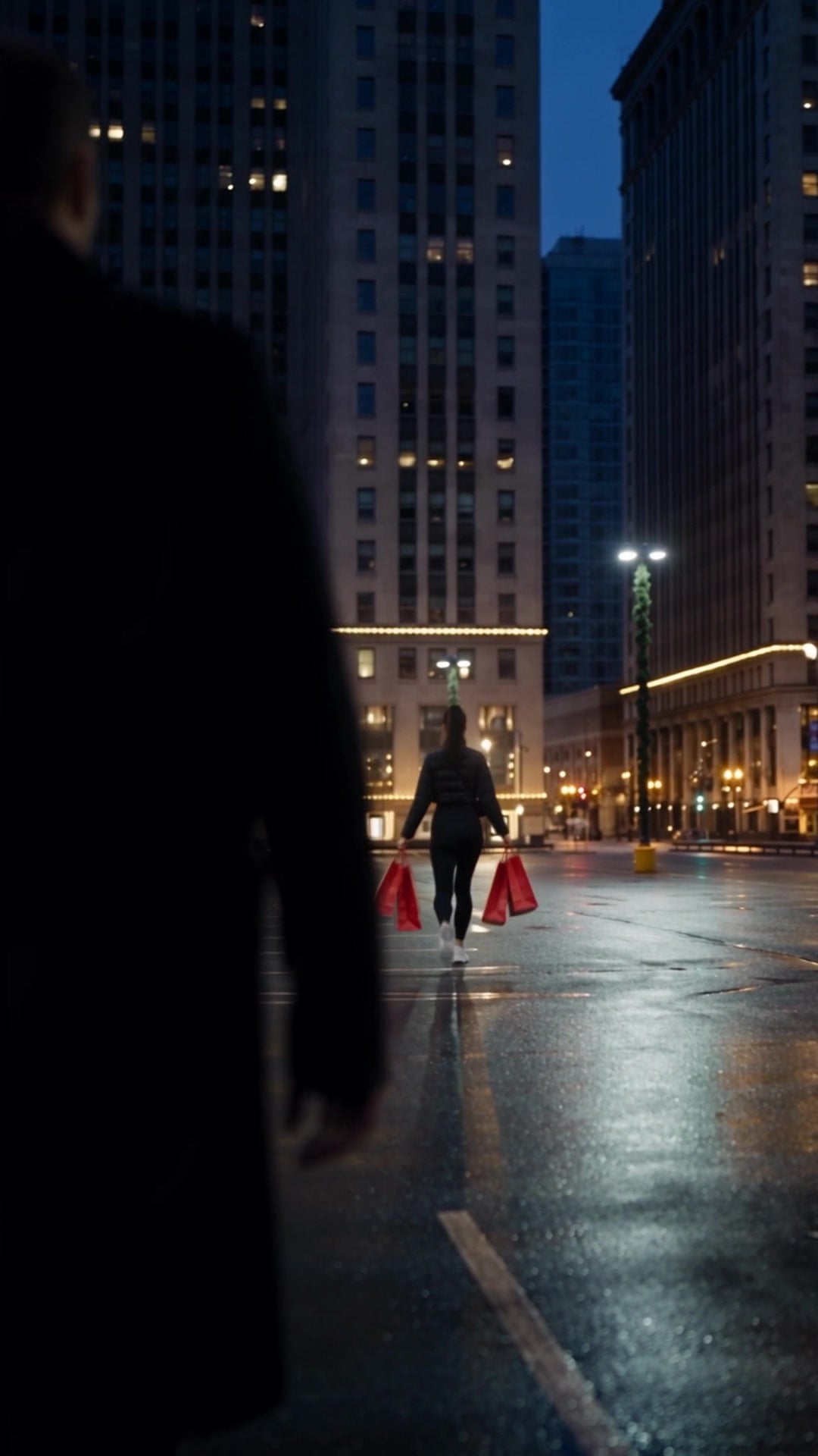 A young woman carrying holiday shopping bags across a nearly empty city parking lot at dusk - Ankin Law dramatization