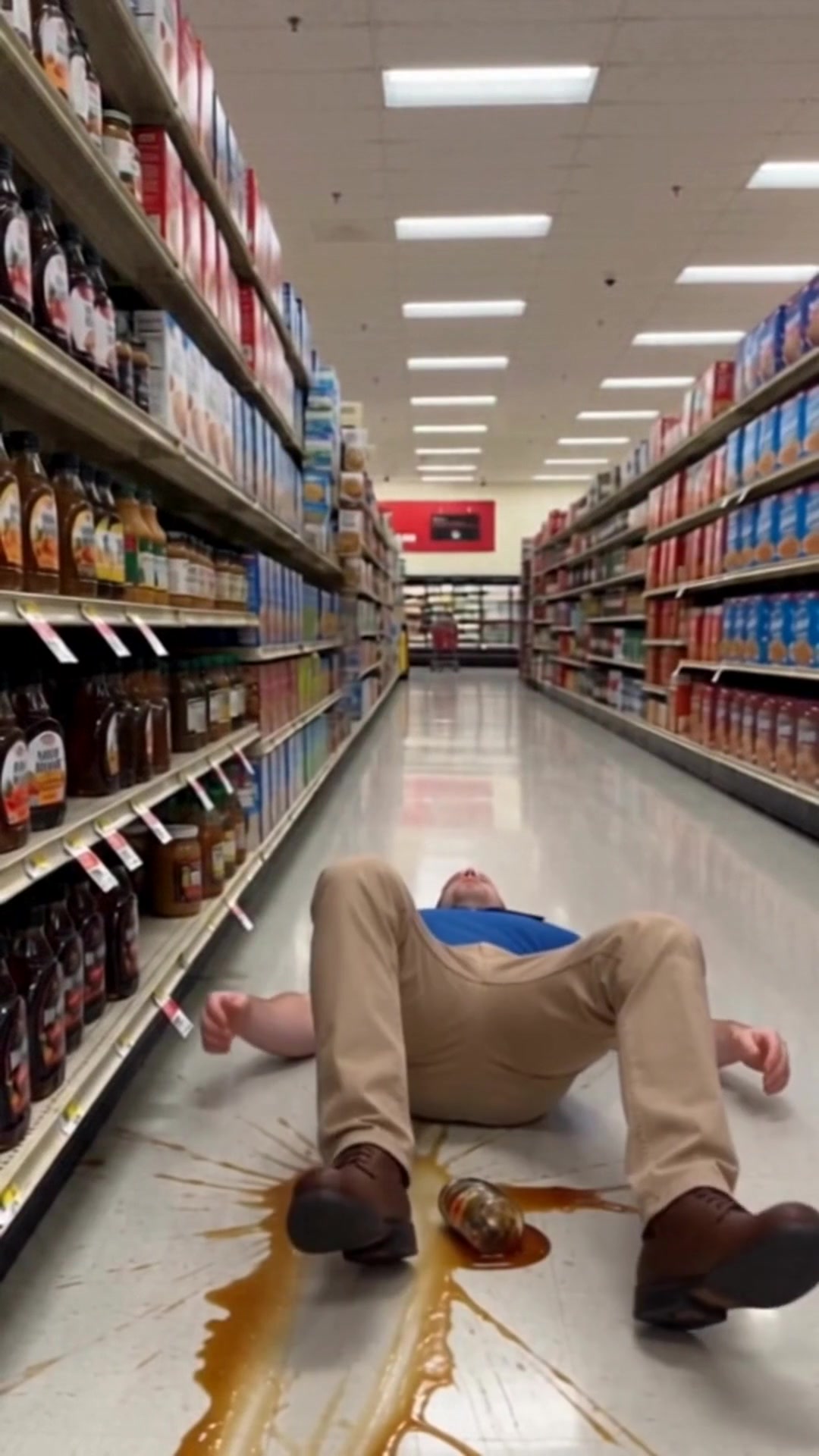 A man on the floor of a store aisle in a spreading spill after slipping - Ankin Law dramatization