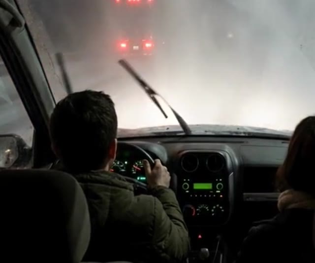 A couple driving a small SUV on a snowy Illinois highway at night behind a semi truck - Ankin Law dramatization