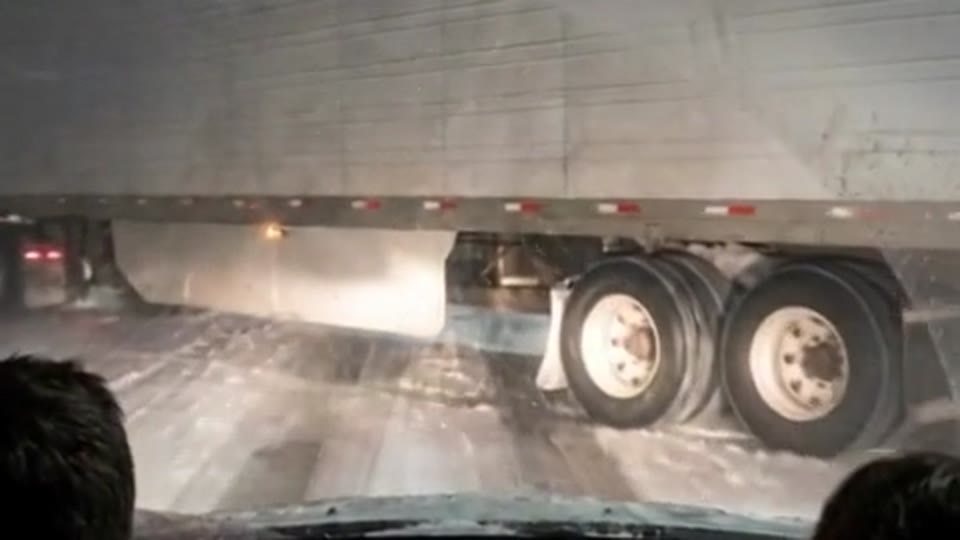 A jackknifed semi trailer blocking every lane of a frozen Illinois bridge in a blizzard