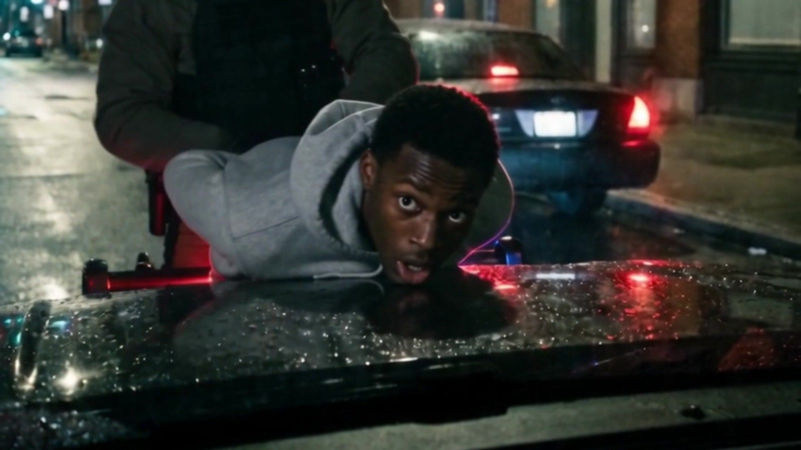 A young man pinned face-down on the hood of a law-enforcement vehicle by a masked ICE agent