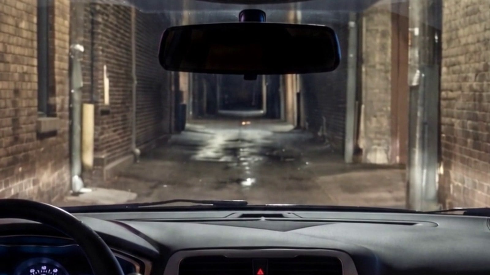 The view from the back seat of a rideshare as the car turns into a dark alley