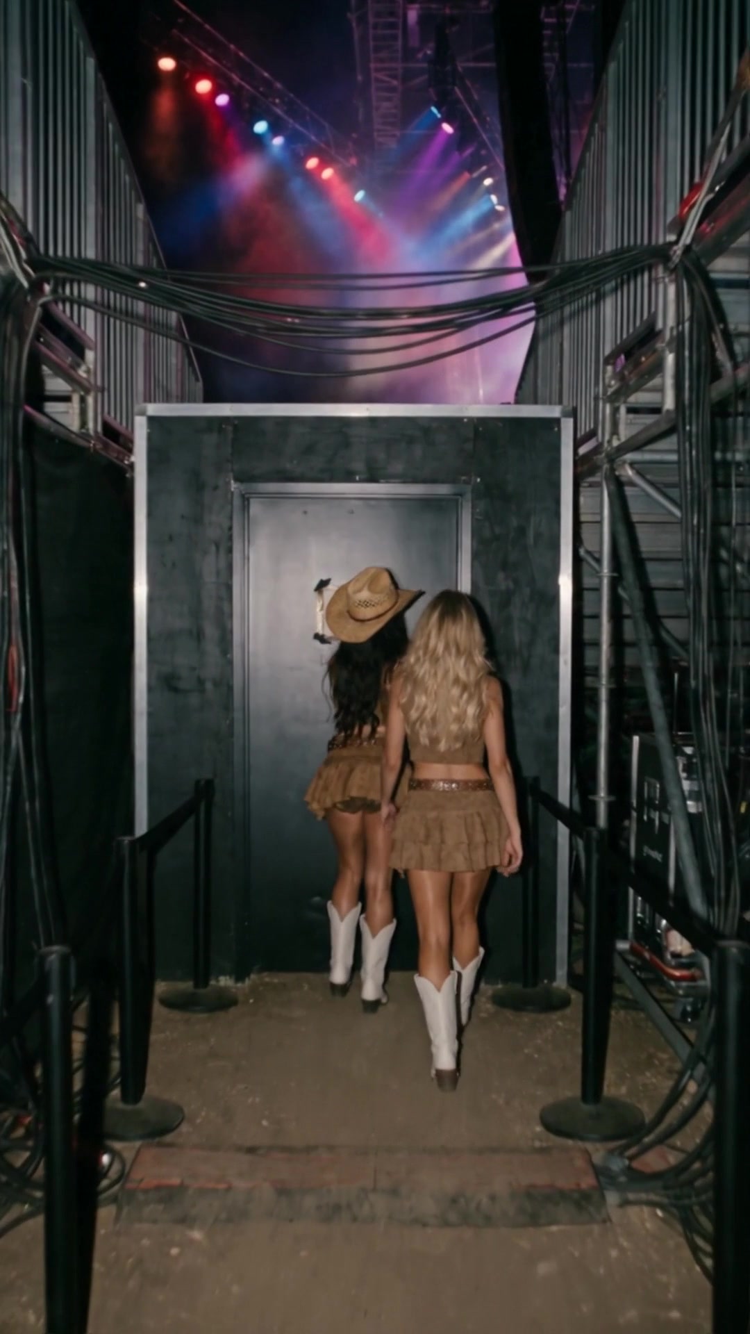 Two young women reaching a black door under a concert stage with the stage lights above - Ankin Law dramatization