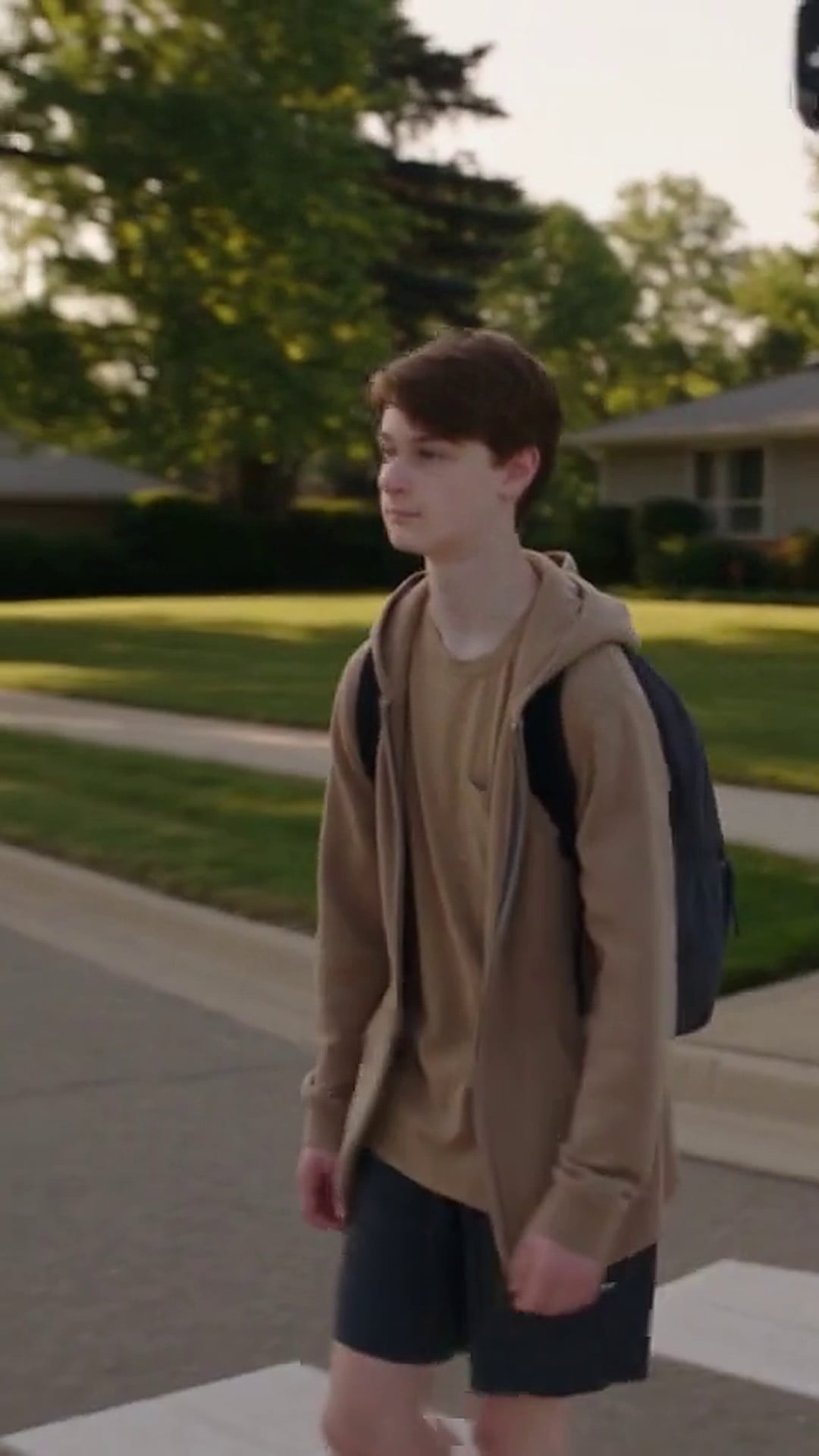 A teenager walking across the white stripes of a marked crosswalk with a backpack - Ankin Law dramatization