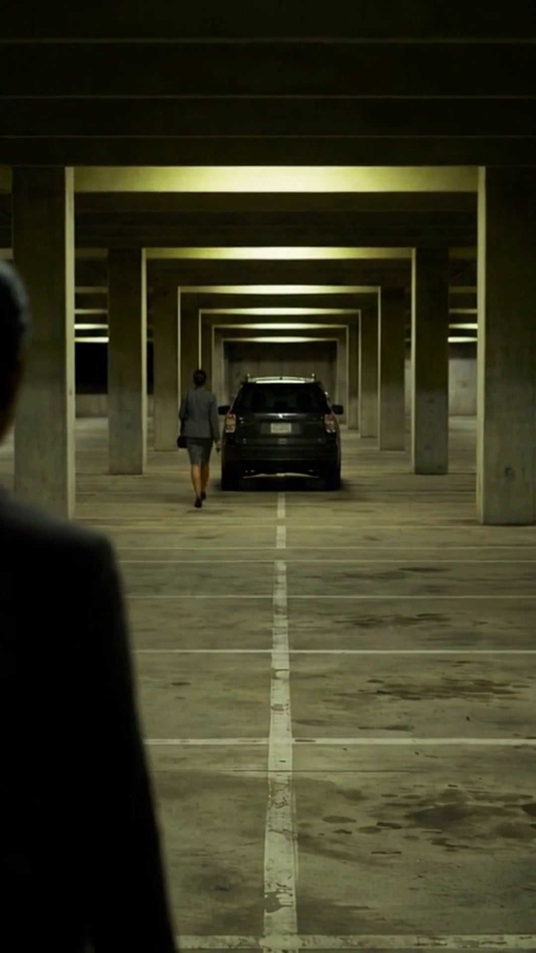 A dark figure stepping out from behind a concrete pillar as a woman reaches her car in a parking garage - Ankin Law dramatization