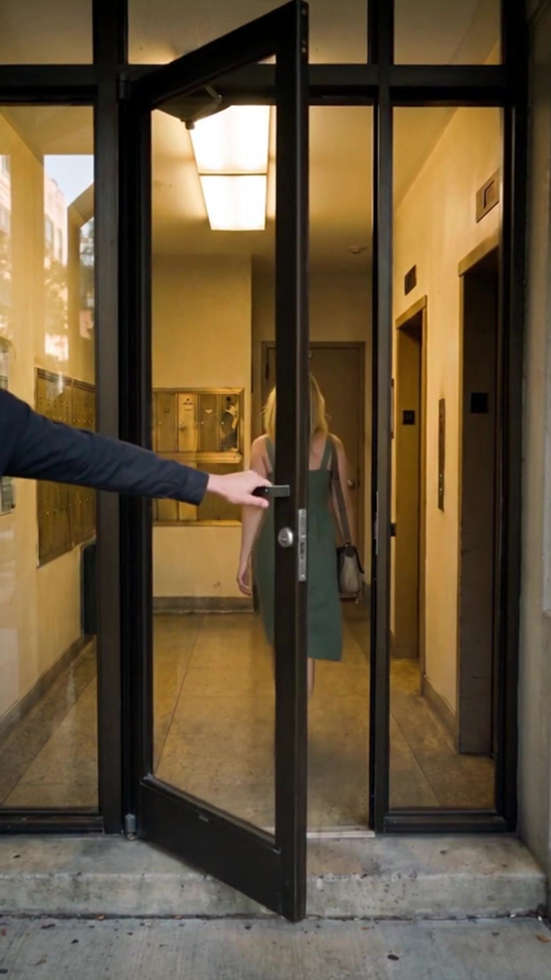A hand catching the lobby door behind a resident who has just walked in - Ankin Law dramatization
