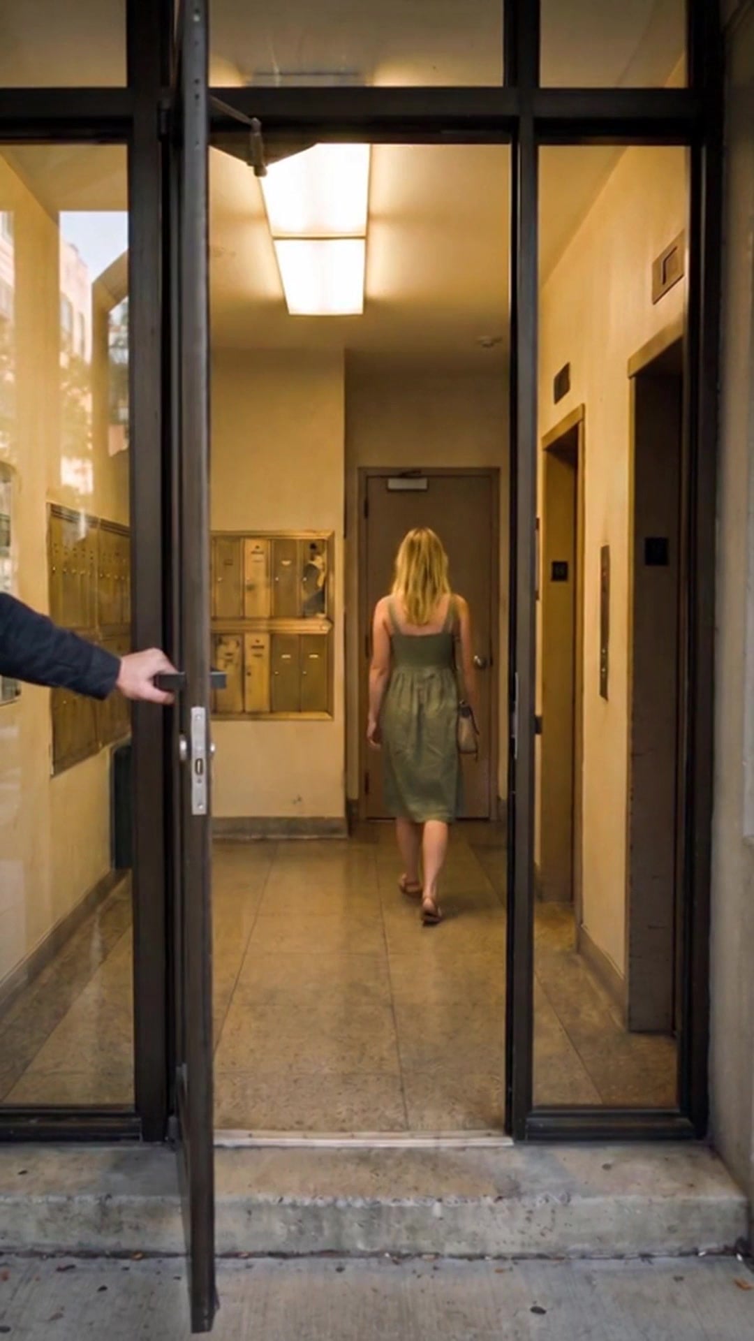 A hand catching a Chicago apartment lobby door as a resident walks in ahead - Ankin Law dramatization