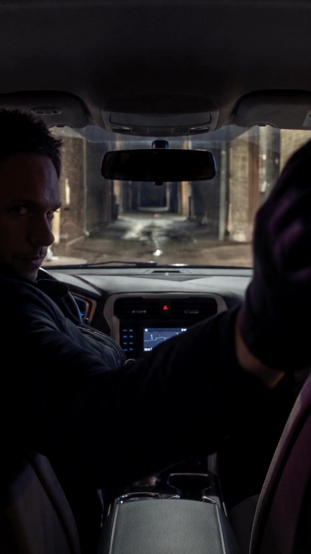 A driver's black-gloved hand reaching back between the front seats of a car - Ankin Law dramatization